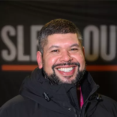 Man smiling in front of Sleep Out signage