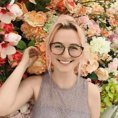Young woman smiling in front of a flower wall