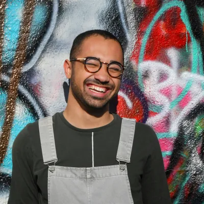 Young man smiling in front of a graffiti wall